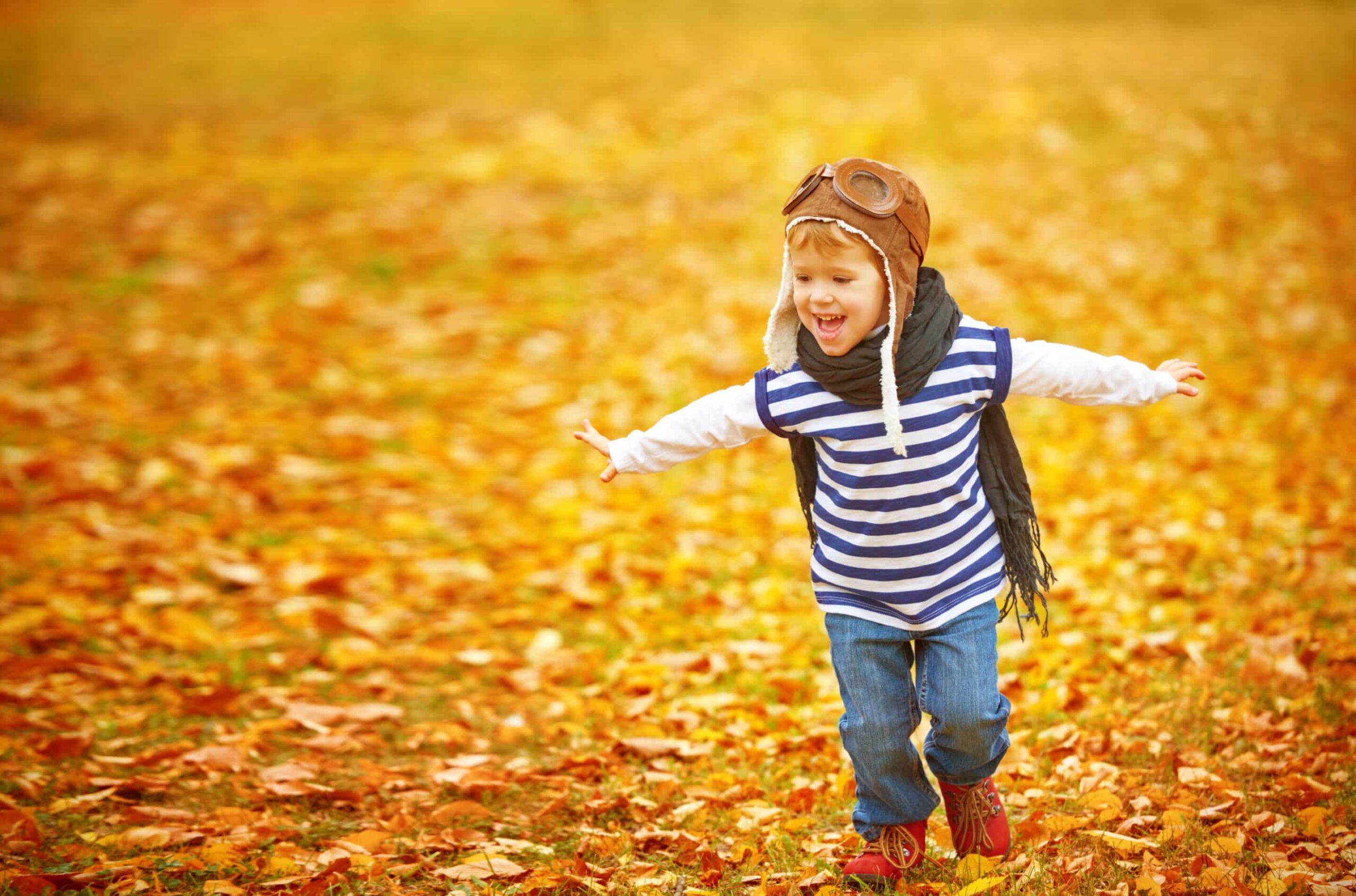 happy child playing pilot aviator outdoors in autumn
