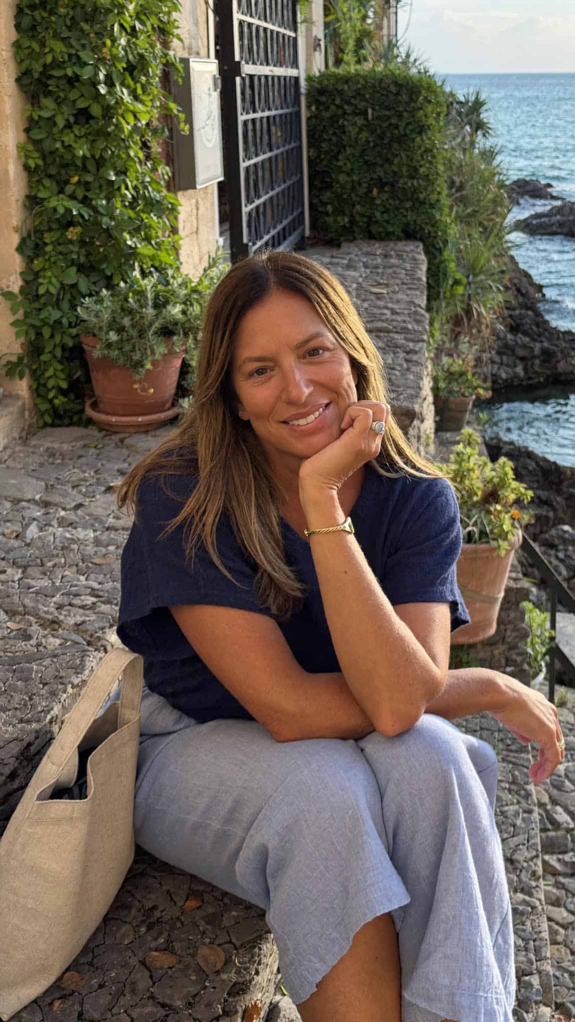 A smiling woman enjoying seaside scenery in Ocean City, Maryland, with ocean views and greenery.