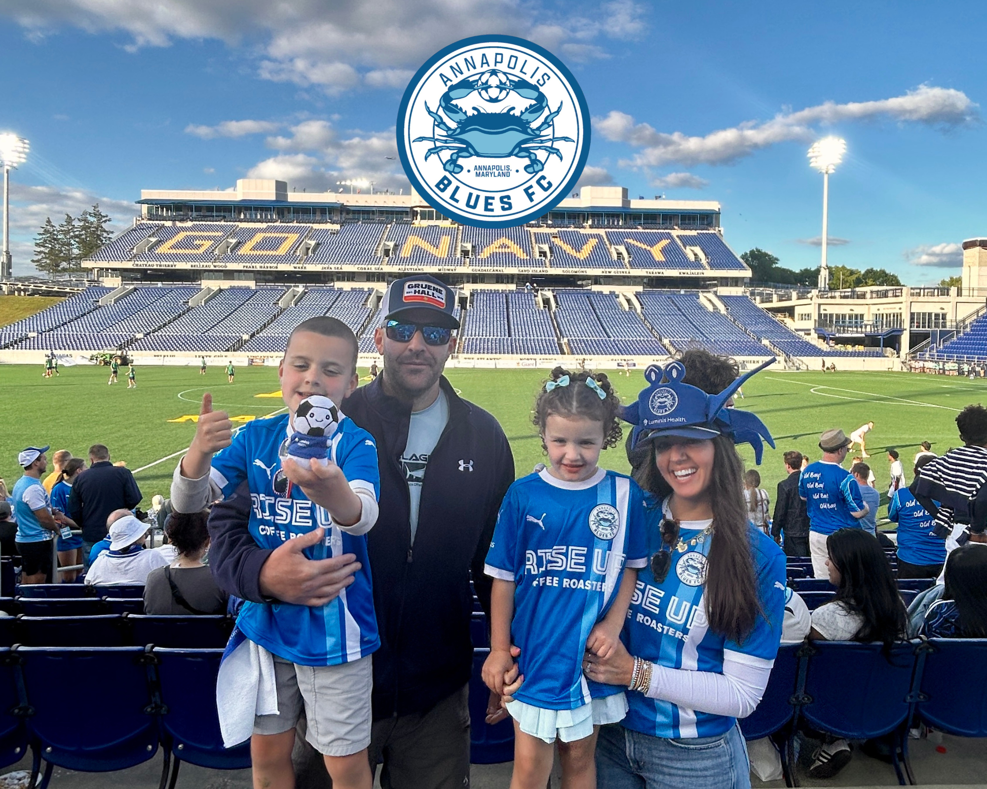 Family at Ocean City Blue's FC game with stadium in background and team gear.