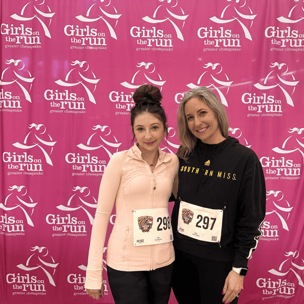 Two women at Girls on the Run event in Ocean City, smiling with pink backdrop.