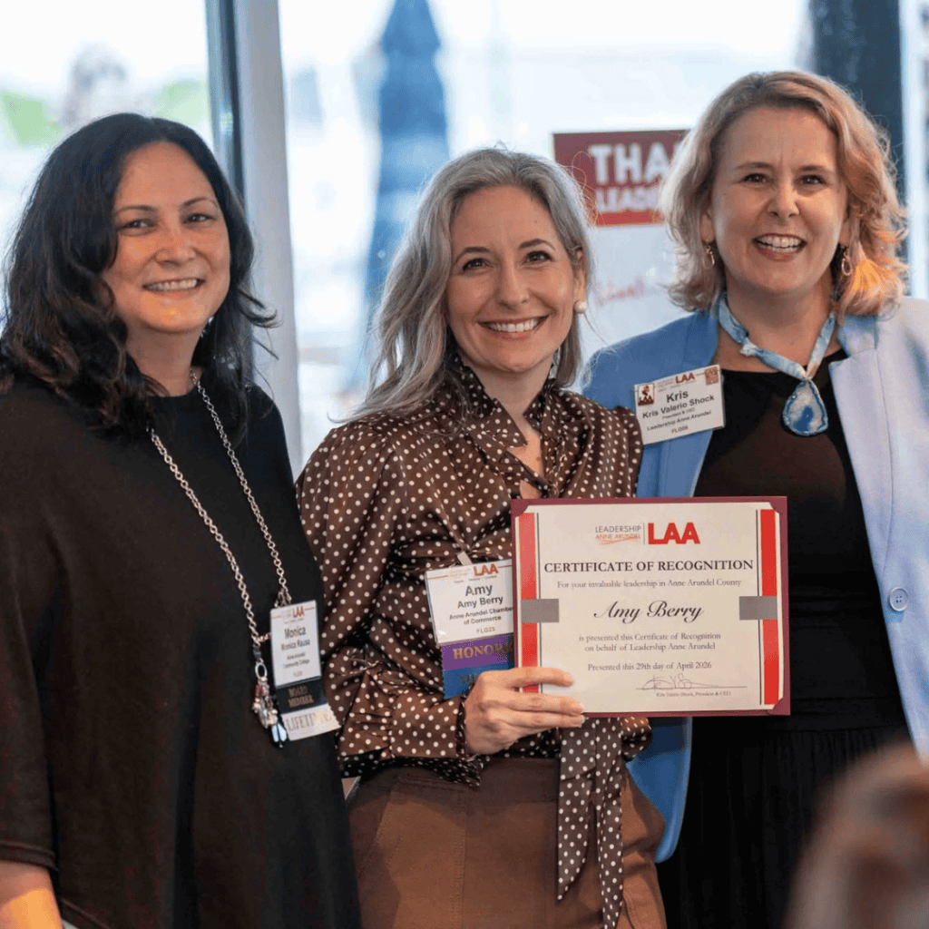 Three women at Ocean City Moms event holding a leadership award certificate, smiling.