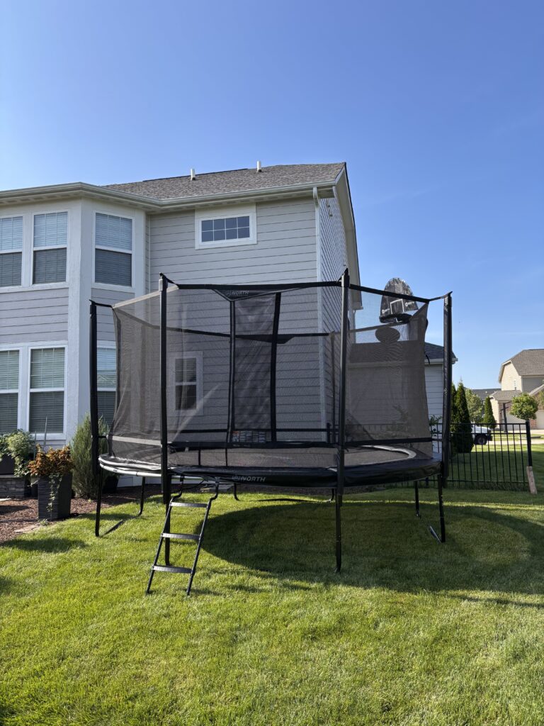 modern trampoline with safety enclosure installed in a family backyard