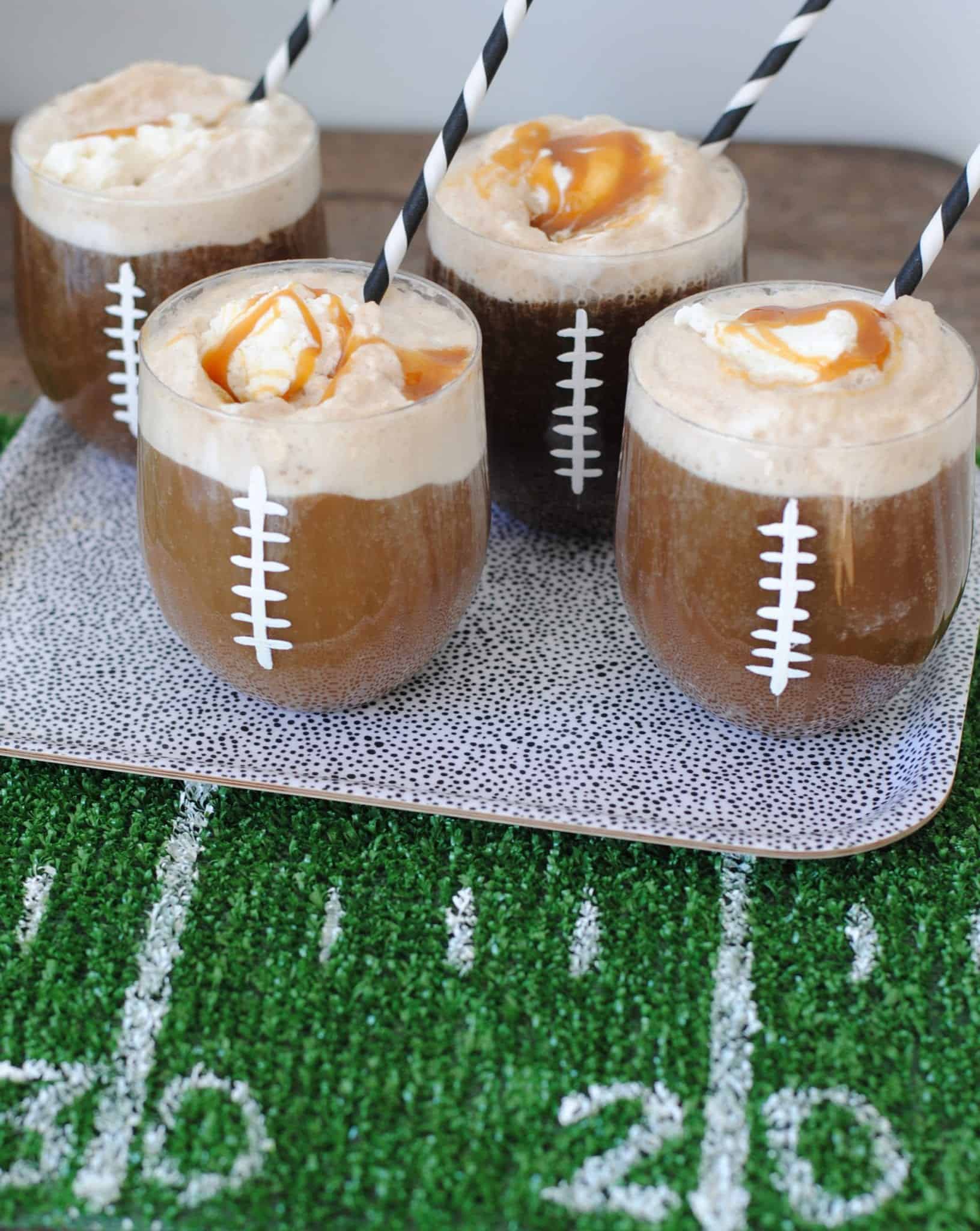 Football-themed drinks with whipped cream and caramel on a green turf table.